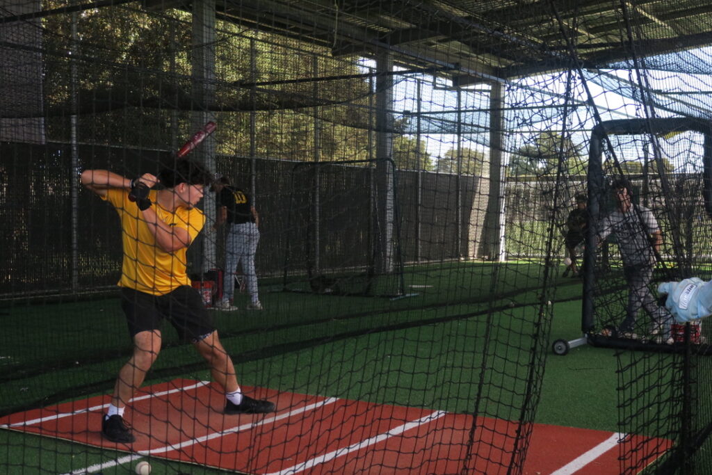 Baseball players practicing batting in batting cage