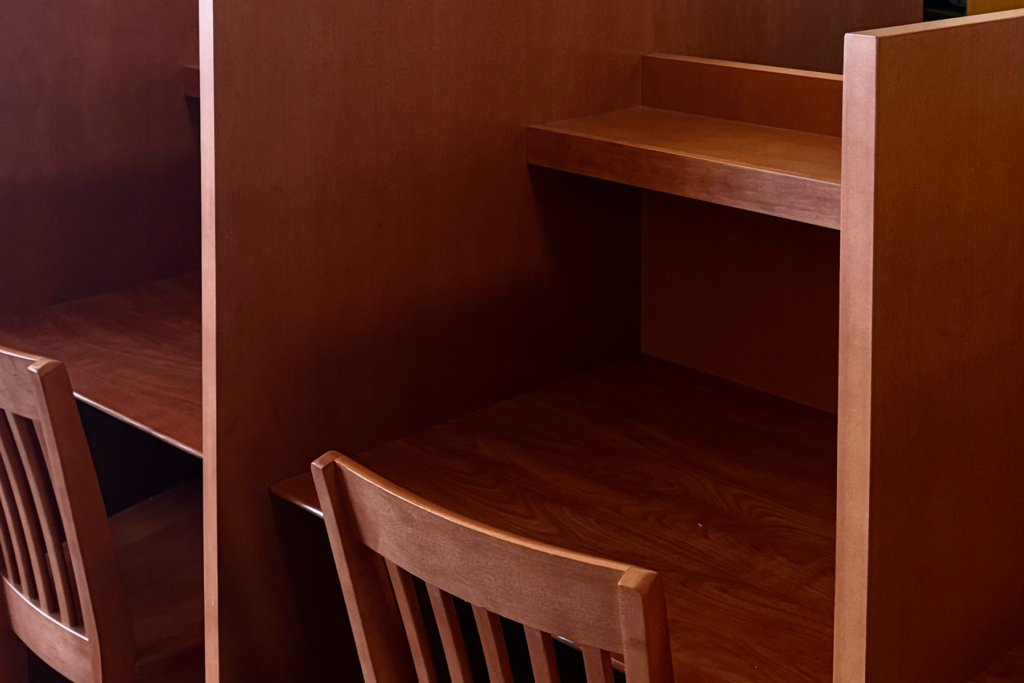 Image features a quiet wooden study cubicle with a chair, a space for studying or reading /Photographed by Diana Cabrera